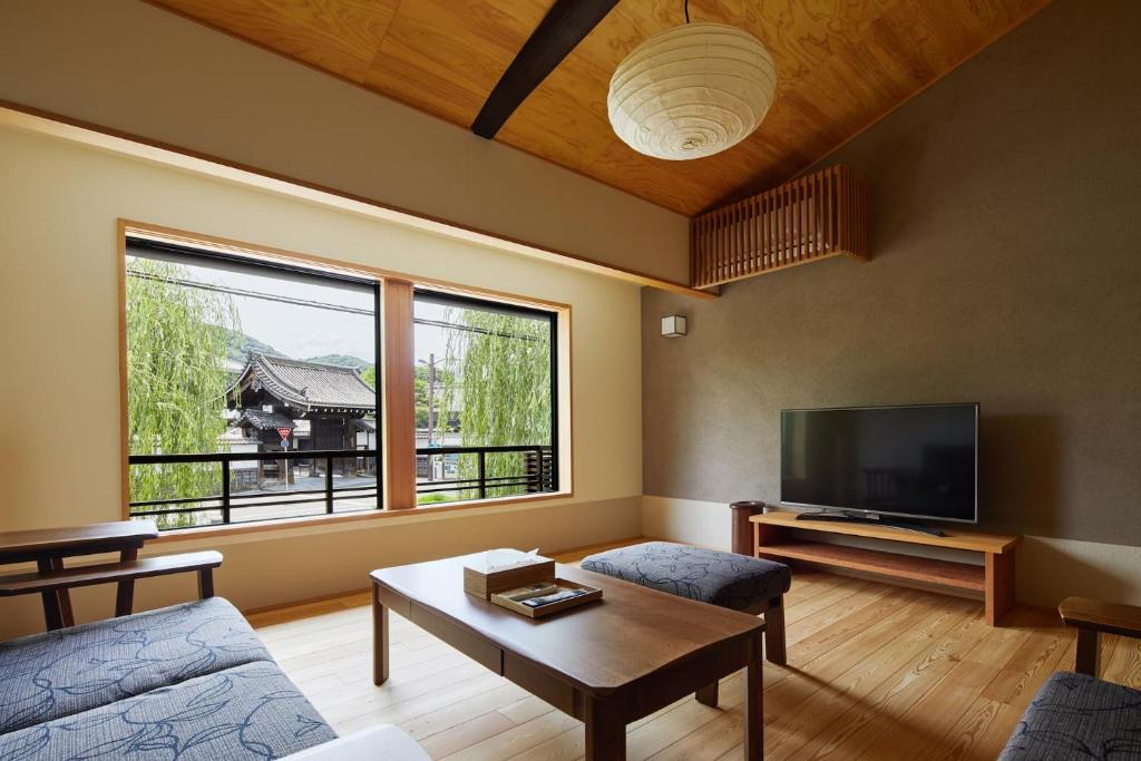 ein Wohnzimmer mit einem Sofa und einem TV in der Unterkunft Gion Shirakawa no Yado by YADORU KYOTO HANARE in Kyoto