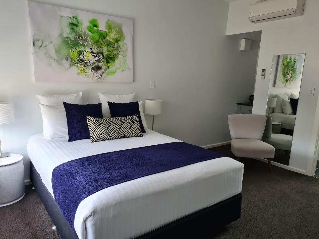 a bedroom with a large bed and a chair at The Avenue Inn in Naracoorte