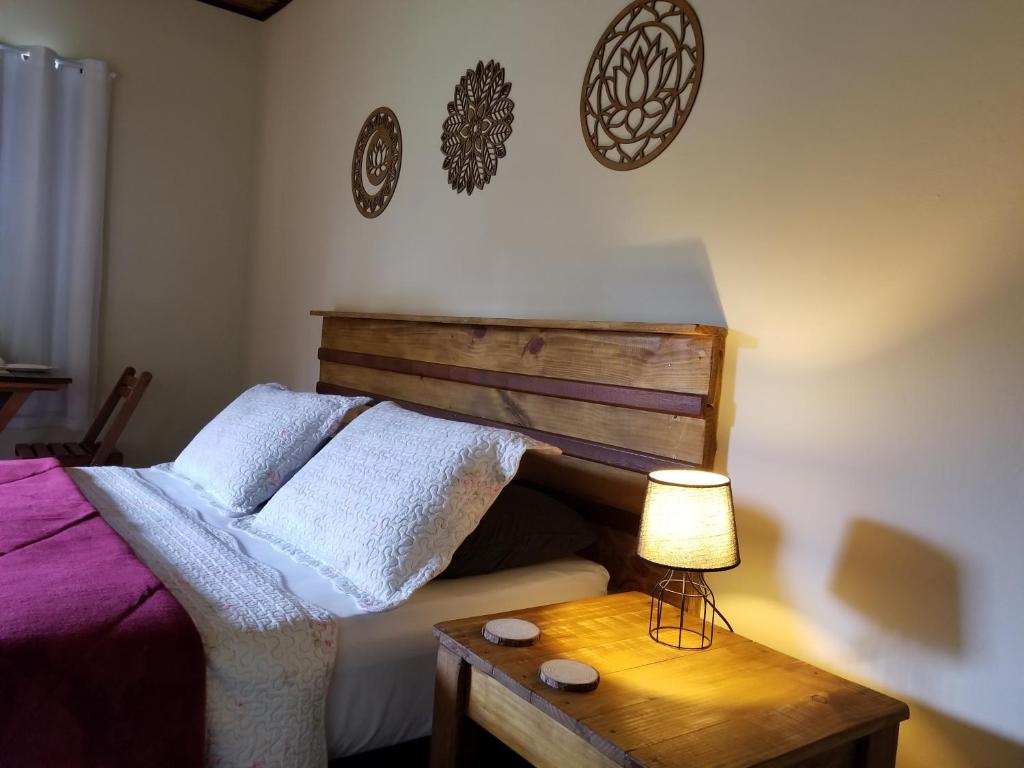 a bedroom with a bed and a table with a lamp at Pousada Verde & Rio Lumiar in Lumiar