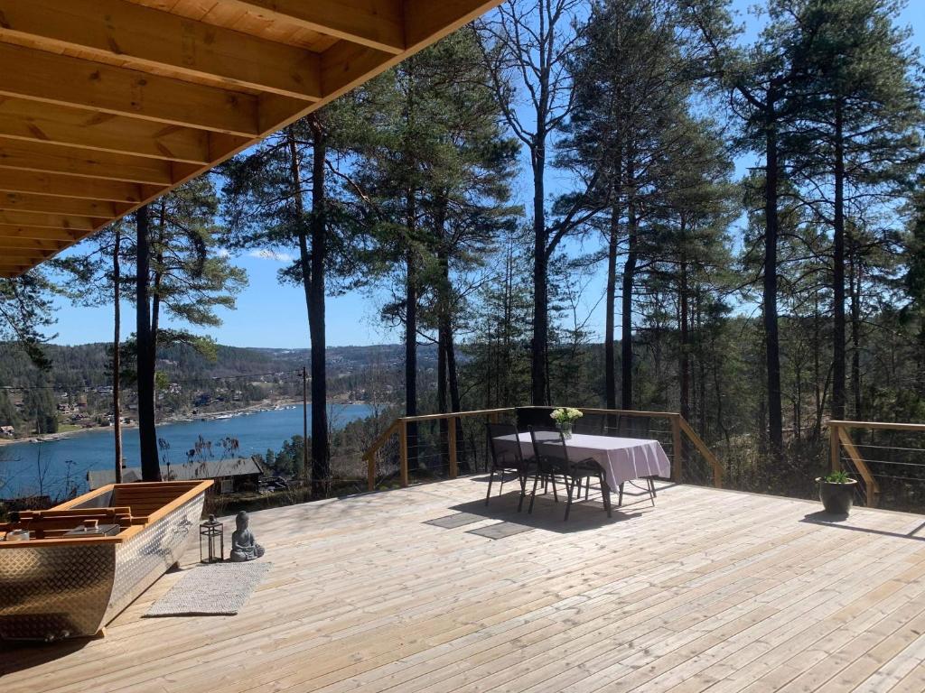 um deque de madeira com uma mesa e vista para um lago em Summer cabin in Nesodden open-air bath large terrace em Brevik