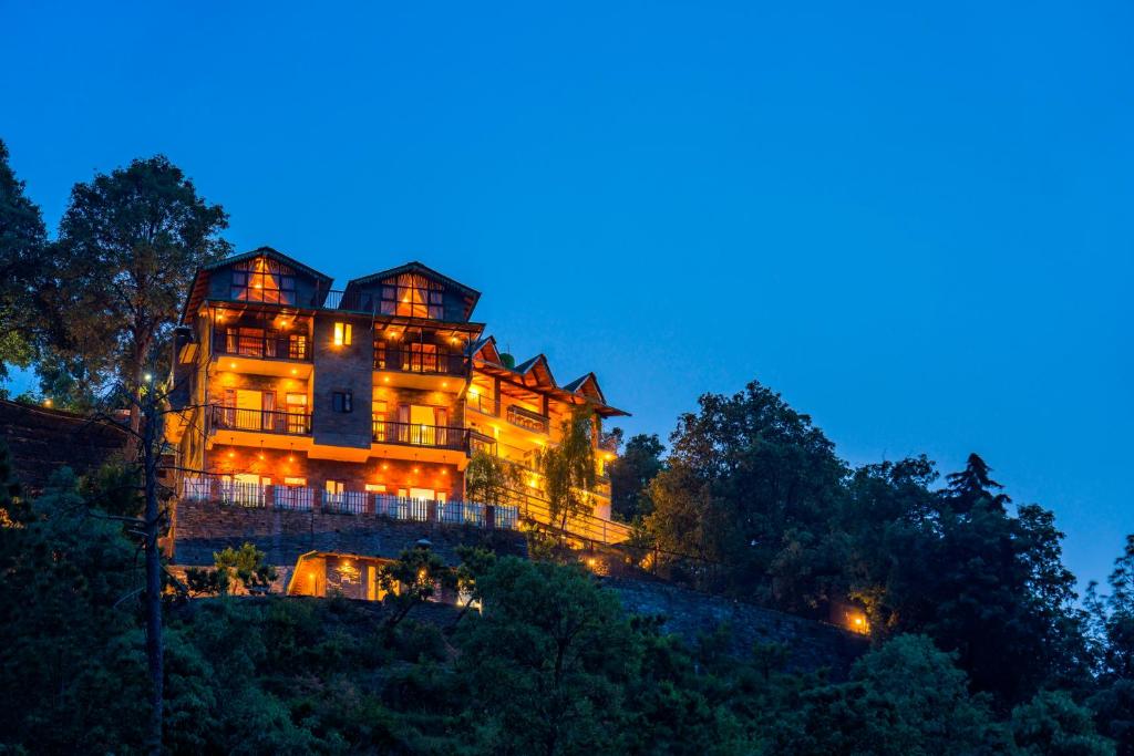 a large house on top of a hill at night at Zostel Homes Ramgarh, Nainital in Rāmgarh