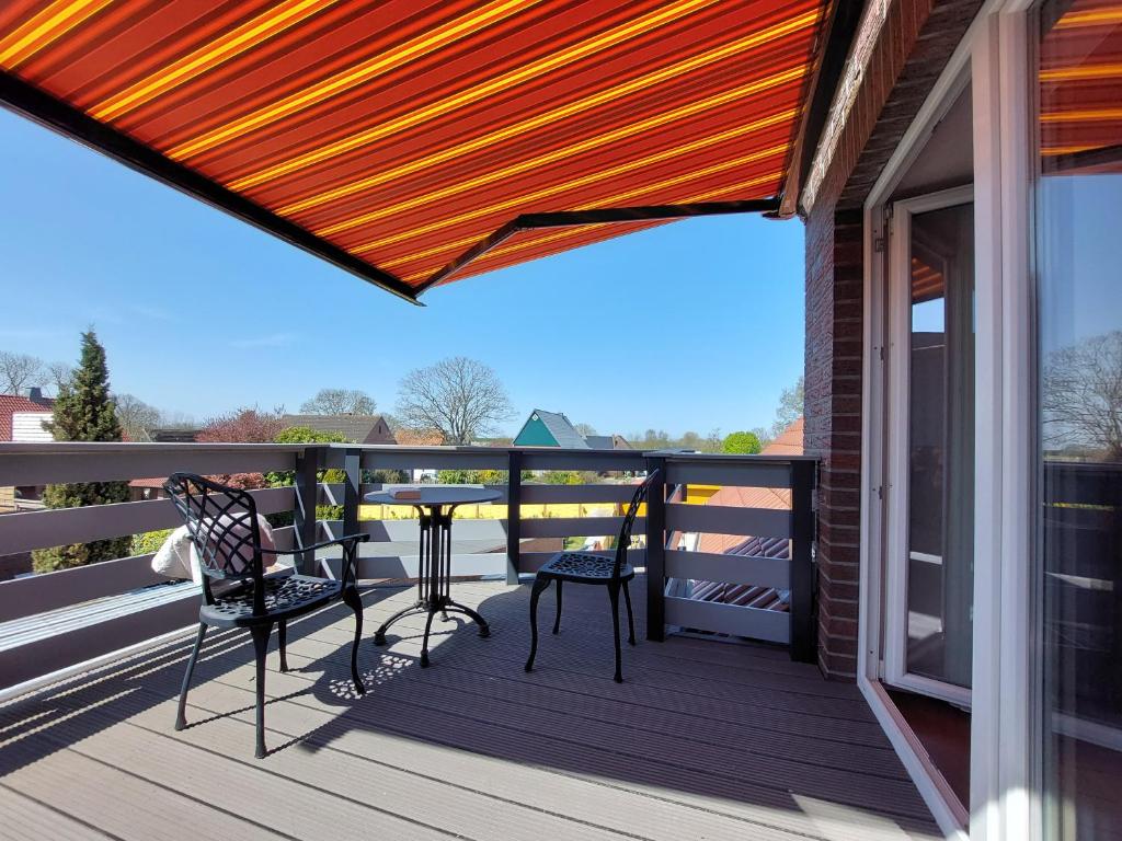 a patio with chairs and a table on a deck at Landhaus Wremer Deel in Wremen