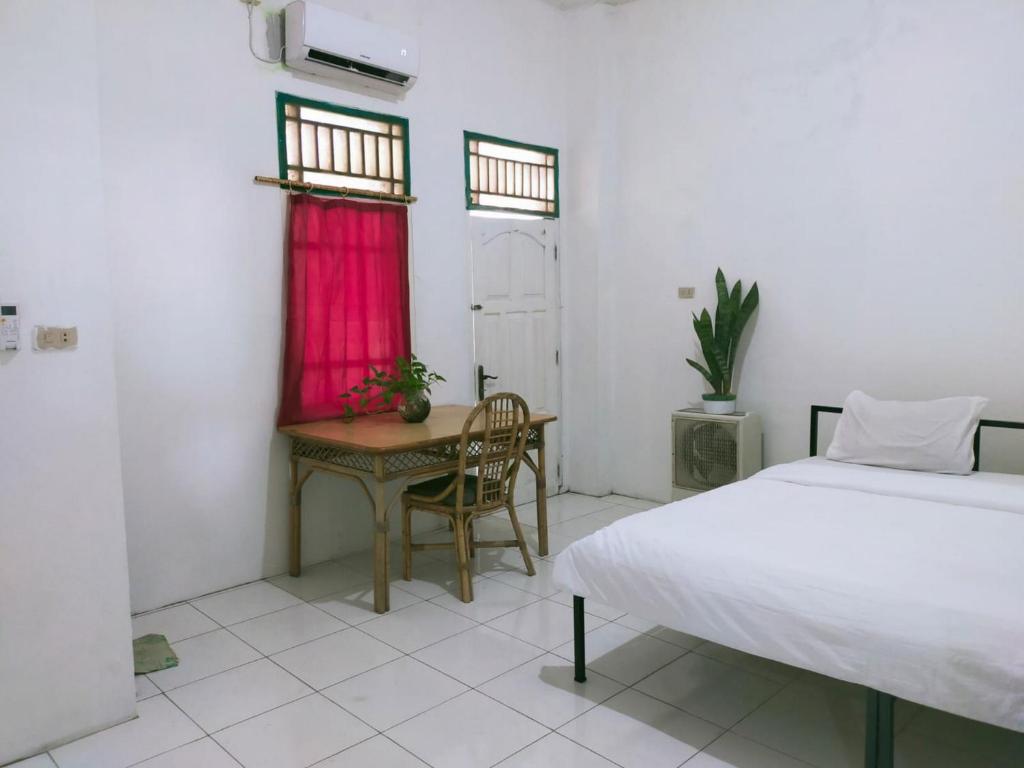 a bedroom with a bed and a desk and a table at Ombai Guest House 27 Syariah Mitra RedDoorz in Kertapati