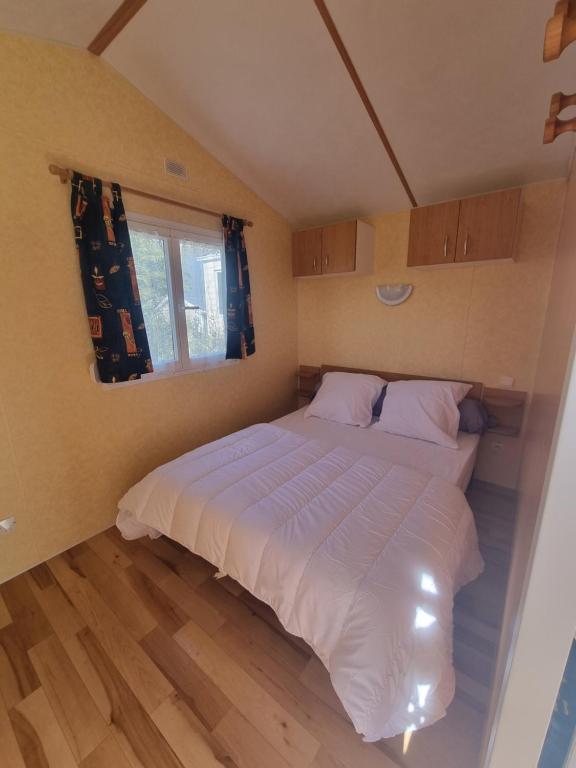 um quarto com uma grande cama branca e uma janela em La belle Perrochoise 13 mobilhome em La Cotinière