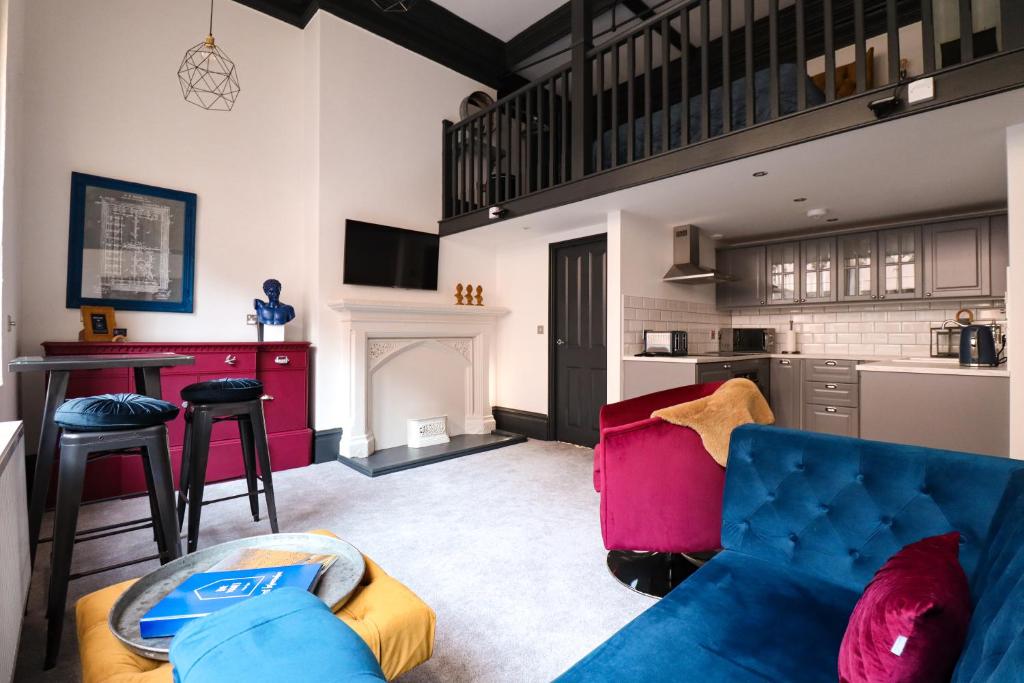 a living room with a blue couch and a kitchen at The Vault - boutique apartment in the centre of King's Lynn in Kings Lynn