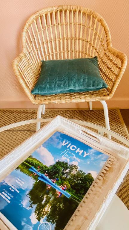 a wicker chair with a pillow on a table at Le Vichy Centre, spacieux et cosy T2 avec vue, au calme in Vichy
