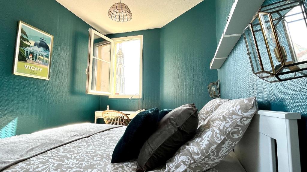 a bedroom with green walls and a bed with pillows at Le Vichy Centre, spacieux et cosy T2 avec vue, au calme in Vichy