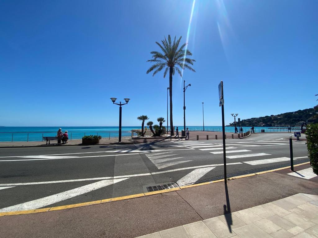 une rue vide avec un palmier et la plage dans l'établissement Cosy 2 pièces, résidence en front de mer, Roquebrune Cap Martin, à Roquebrune-Cap-Martin
