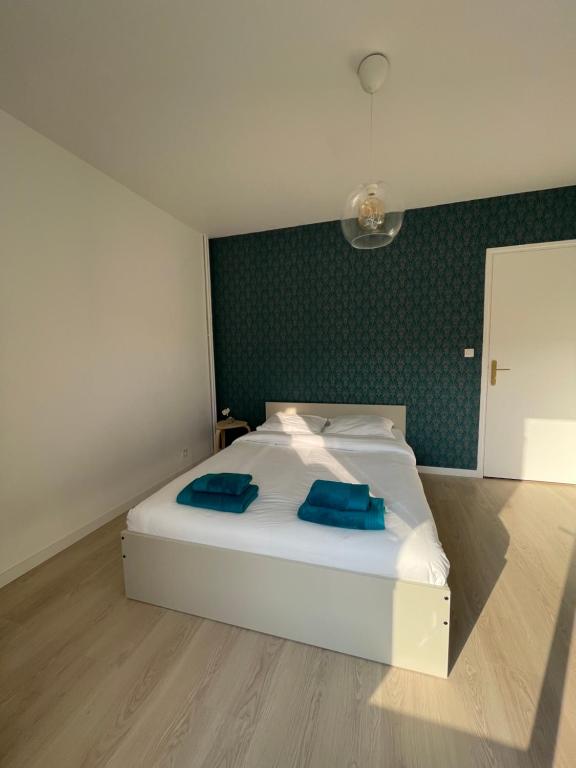 a bedroom with a white bed with blue pillows on it at Le Cerisier in Meulers