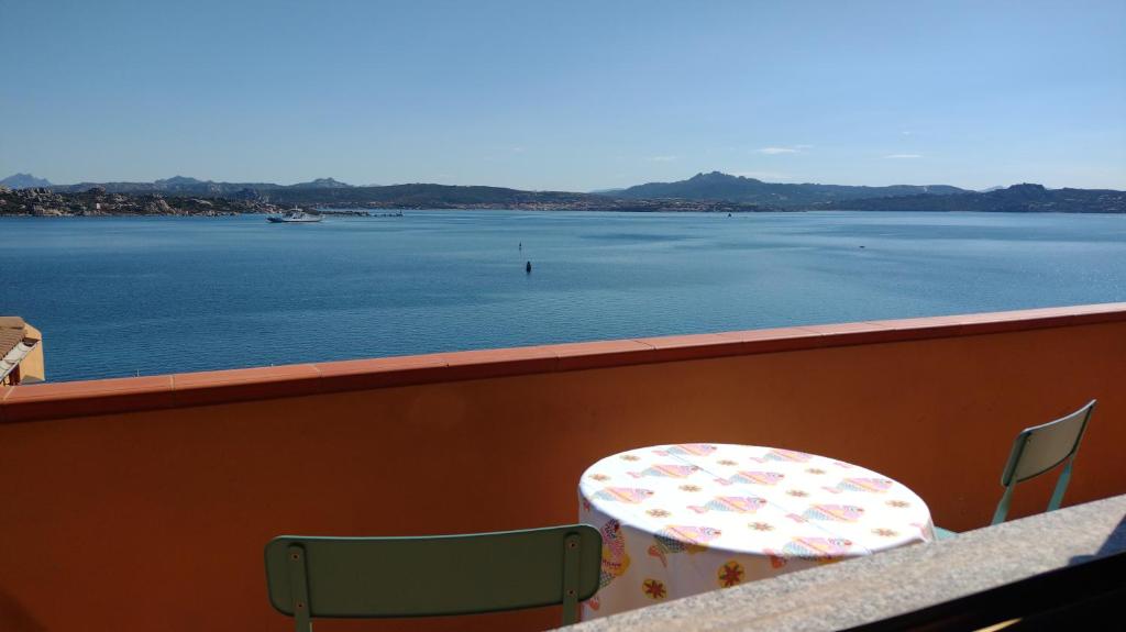 stół i krzesła na balkonie z widokiem na wodę w obiekcie Appartamentino panoramico...con finestra sul mare! w mieście La Maddalena