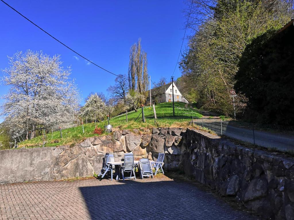 un groupe de chaises assises à côté d'un mur en pierre dans l'établissement Gîte Henry, à Orbey