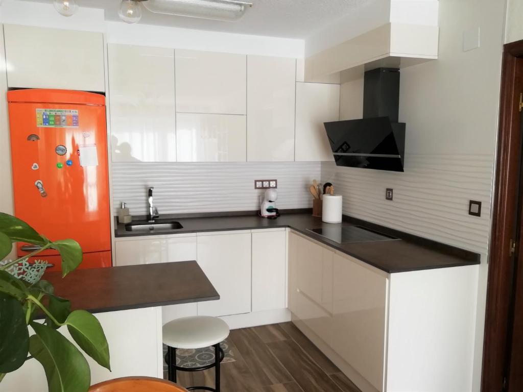 a kitchen with white cabinets and an orange refrigerator at Apartamento a 30 metros de la playa in San Vicente de la Barquera