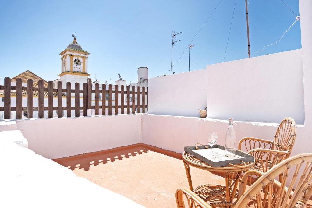 un patio con mesa y sillas y una torre del reloj en Casa Pepa, en Chiclana de la Frontera