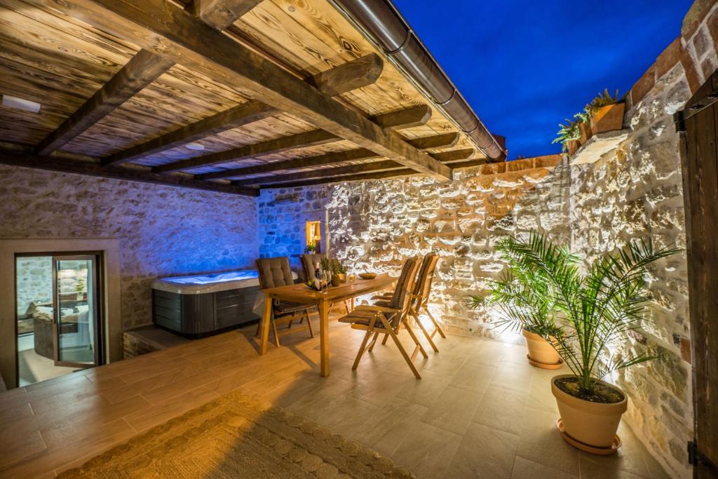 Habitación con mesa, sillas y pared de piedra. en Roman style stone Villa Lux Solis, en Nin