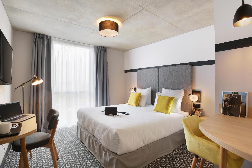 布拉尼亚克Appart Hotel Odalys City Toulouse Blagnac Aéroport的配有一张大床和一张书桌的酒店房间