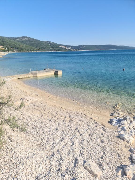 a sandy beach with a dock in the water at Apartments Pinezić in Martinšćica