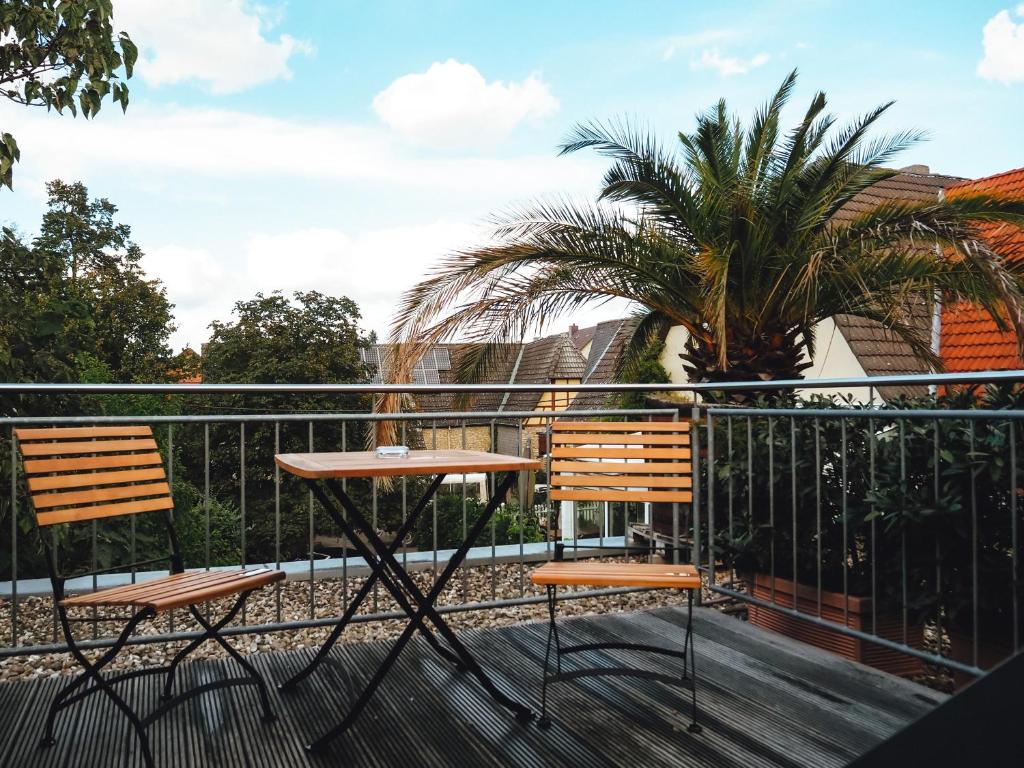 a table and two chairs on a balcony with a palm tree at Weinhotel Wasem in Ingelheim am Rhein