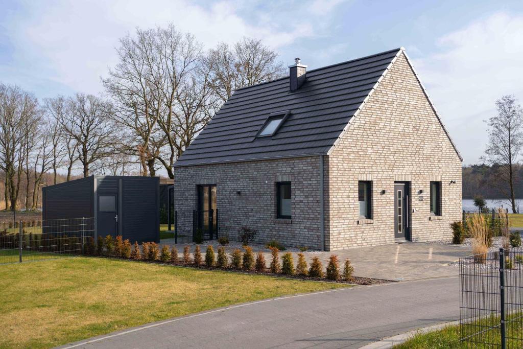 a small brick house with a black roof at Haus Seerose direkt am Harkebrügger See Neubau! in Barßel