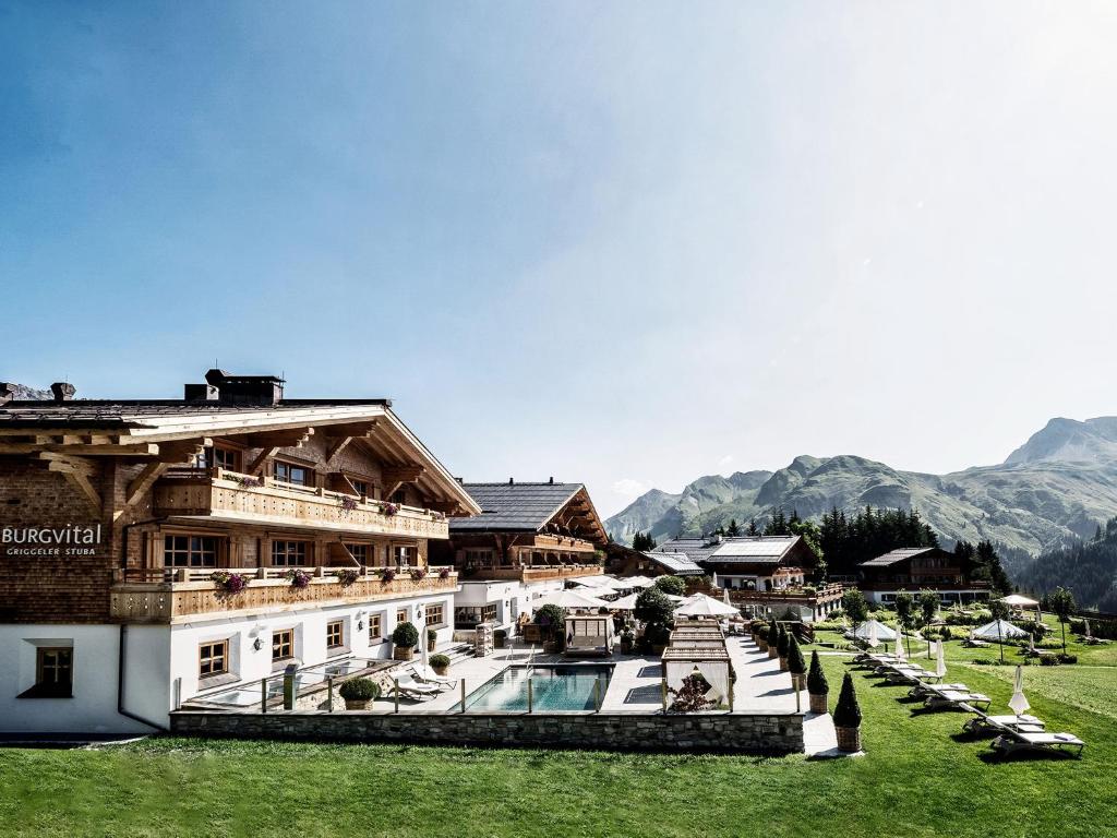 un complejo con piscina y montañas de fondo en Burg Vital Resort, en Lech am Arlberg