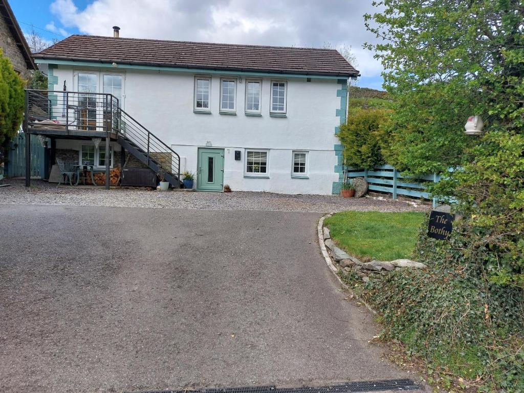 a white house with a green door and a driveway at THE BOTHY SUITE BY TEMPLE WOOD in Lochgilphead