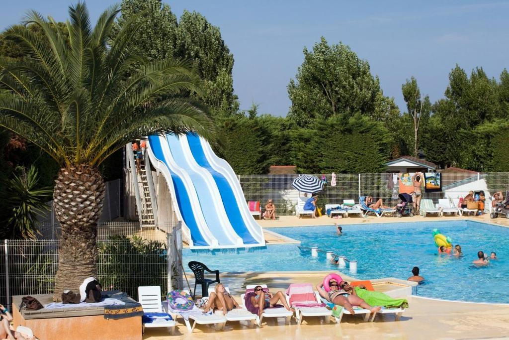 a pool with a slide and people at a resort at Camping les salins de la gardiole, mobile home 6 personnes in Vic-la-Gardiole