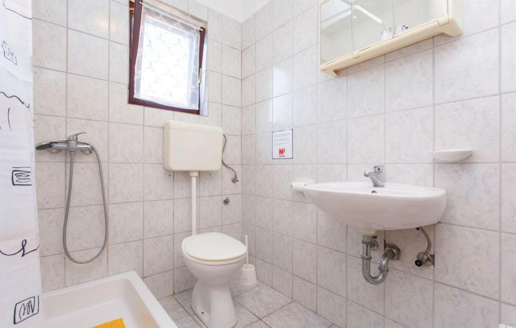 biała łazienka z toaletą i umywalką w obiekcie Apartmani Mile w Krku