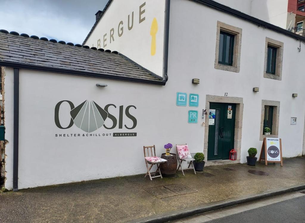 a white building with a sign on the side of it at Albergue Oasis in Sarria