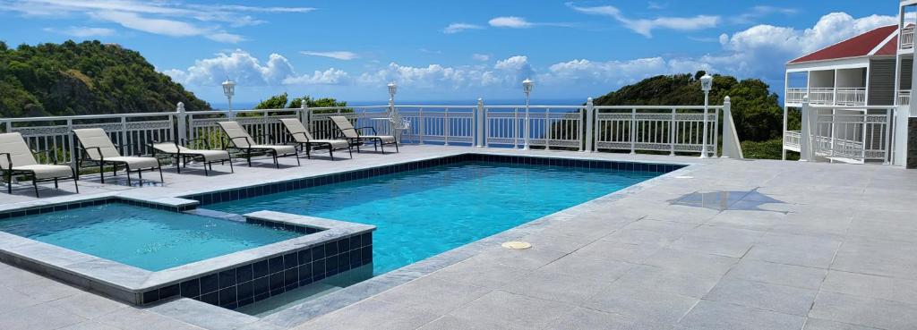 a swimming pool on a patio with chairs and the ocean at Saba Arawak Hotel in Windwardside