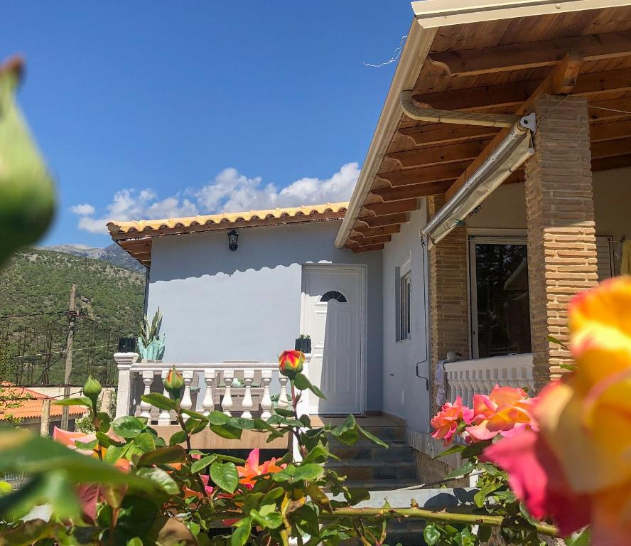 una piccola casa con una porta bianca e fiori di Milos Apartments a Himare