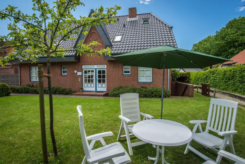 einen Tisch und Stühle sowie einen Regenschirm vor einem Haus in der Unterkunft Haus Albatros Whg 04 in Wyk auf Föhr