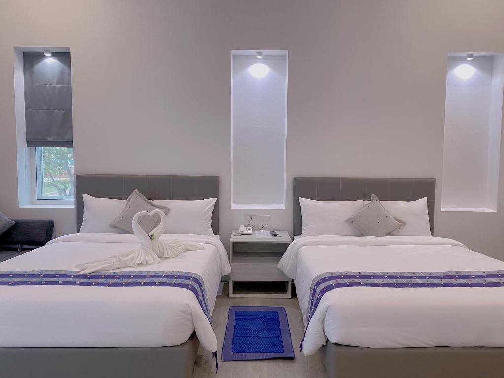 1 dormitorio con 2 camas con sábanas blancas en GRAND PA Hotel&Resort Lamphun Chiang Mai en Lamphun