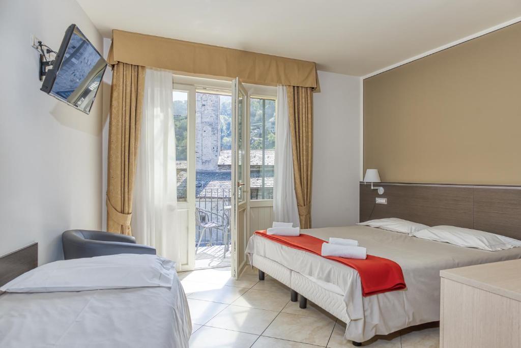 Cremiaにあるホテル ルミンのベッド2台とバルコニーが備わるホテルルームです。