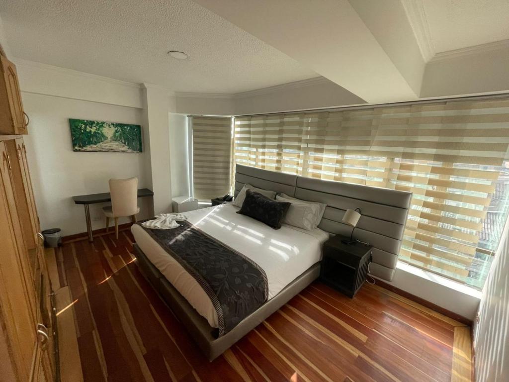 ein Schlafzimmer mit einem Bett, einem Schreibtisch und einem Fenster in der Unterkunft Hotel Airport Travel in Bogotá