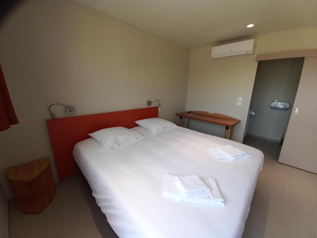 a bedroom with a large white bed with two white pillows at Hôtel La Croix de Mille in Pampelonne