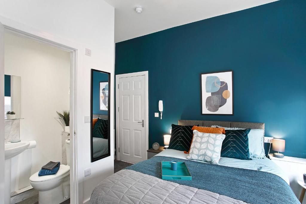 a blue bedroom with a bed with a blue accent wall at Averill Street Guest house in Manchester