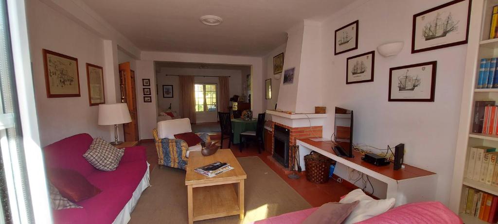 a living room with a red couch and a table at Vivenda Faria in Vila Nova de Milfontes
