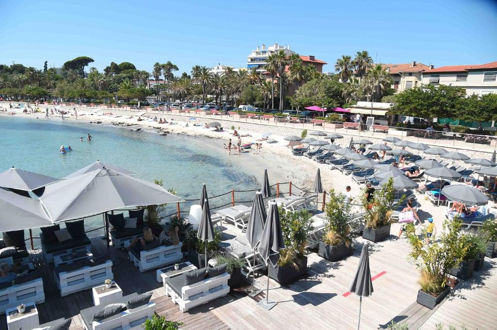 a swimming pool with chairs and a beach with people at Royal Antibes - Luxury Hotel, Résidence, Beach & Spa in Antibes