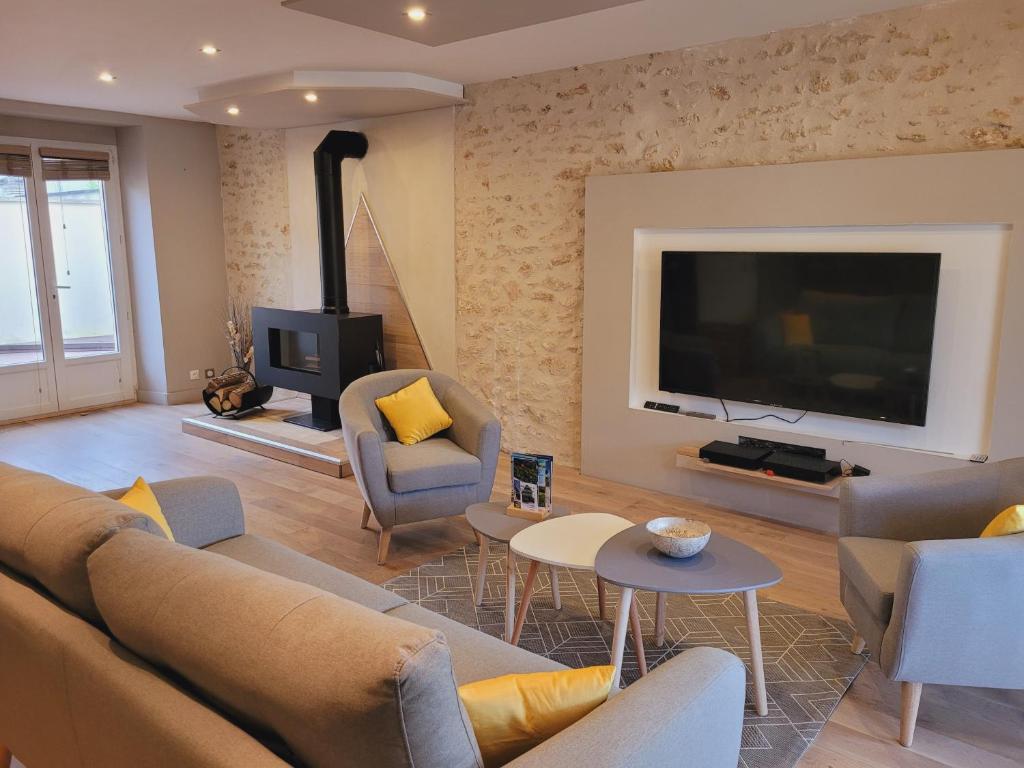 a living room with a couch and a tv at L'inattendu, jolie maison briarde avec jacuzzi in Chenoise