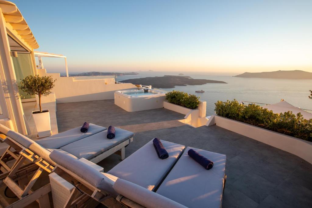 um pátio com mesas azuis e uma banheira em Sunset View Villa Santorini - with Outdoor Jacuzzi em Firostefani