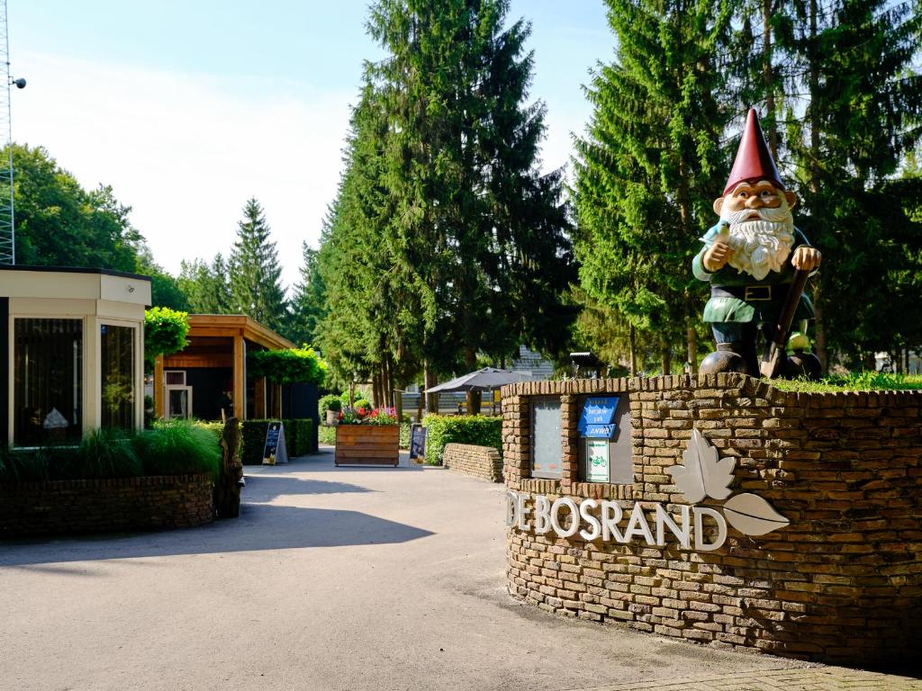 a sign for a resort with a gnome on a wall at Vakantiepark de Bosrand in Vaassen