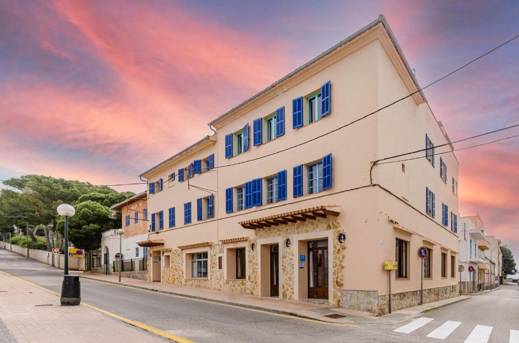 un edificio blanco con ventanas azules en una calle en Hostal Marina, en Cala Ratjada