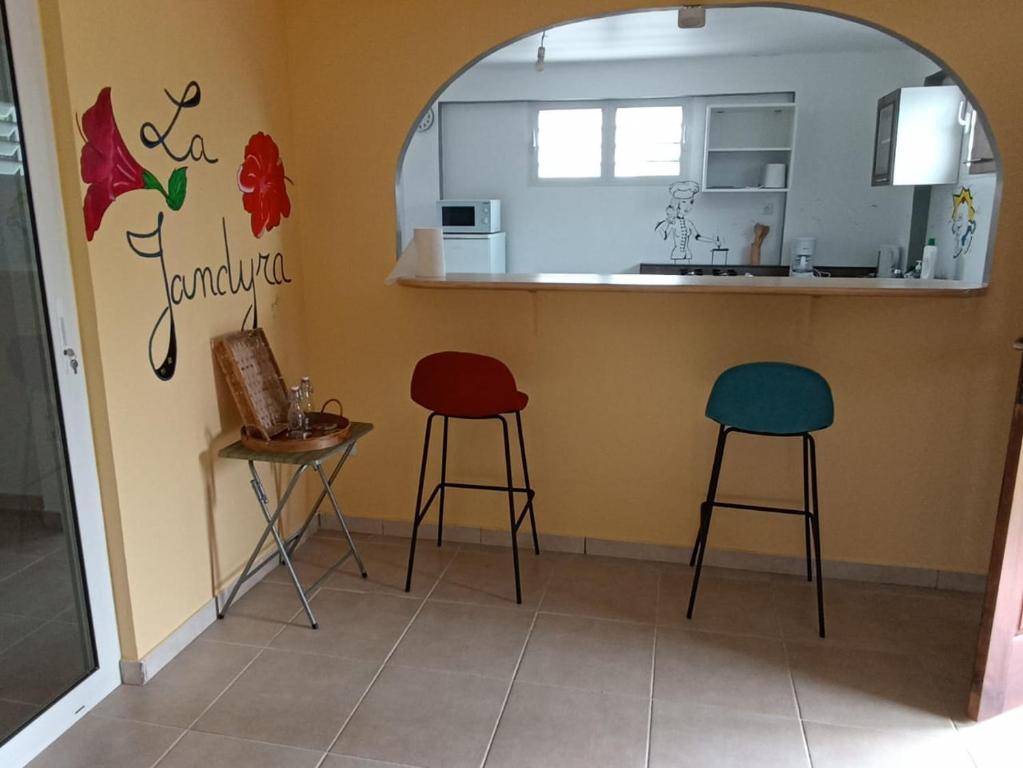 a kitchen with two stools and a counter in a room at La Jandyra in Gros-Morne