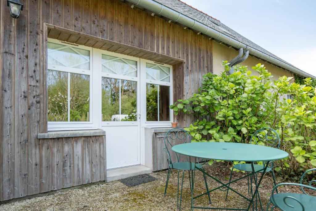 eine Terrasse mit einem Tisch und Stühlen vor einem Gebäude in der Unterkunft Gîte Le Bisquin in Cancale