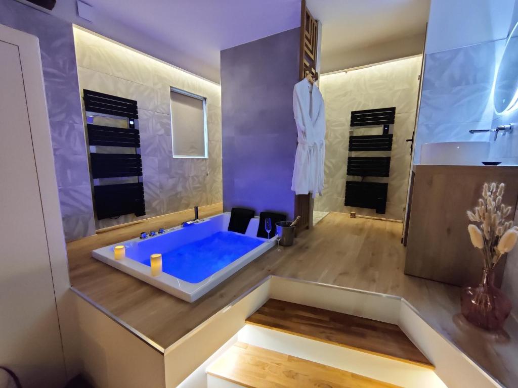 uma casa de banho com uma banheira azul e um lavatório. em LA BULLE ROMANTIQUE, Suite avec jacuzzi privatif 