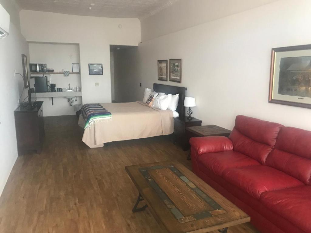 a living room with a bed and a red couch at Katie's Cozy Suites in Tombstone