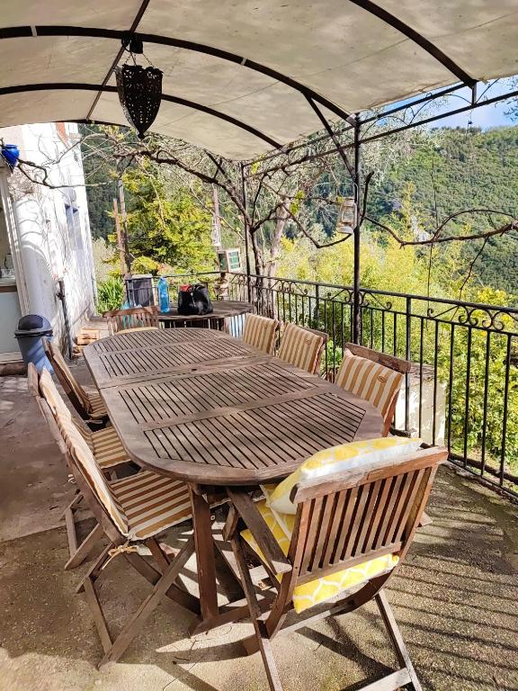 une table et des chaises en bois sous un parasol sur une terrasse dans l'établissement Maison charmante à Peille + jardin, à Peille