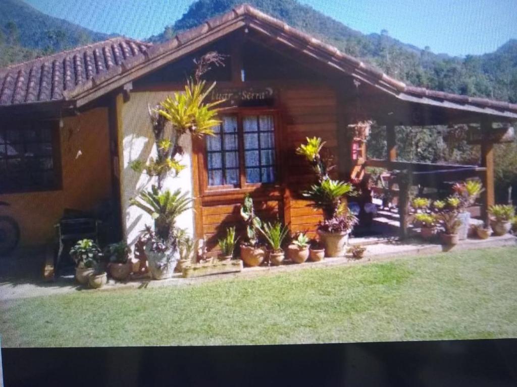 a house with potted plants in front of it at OYO Pousada Luar da Serra Lumiar in Lumiar