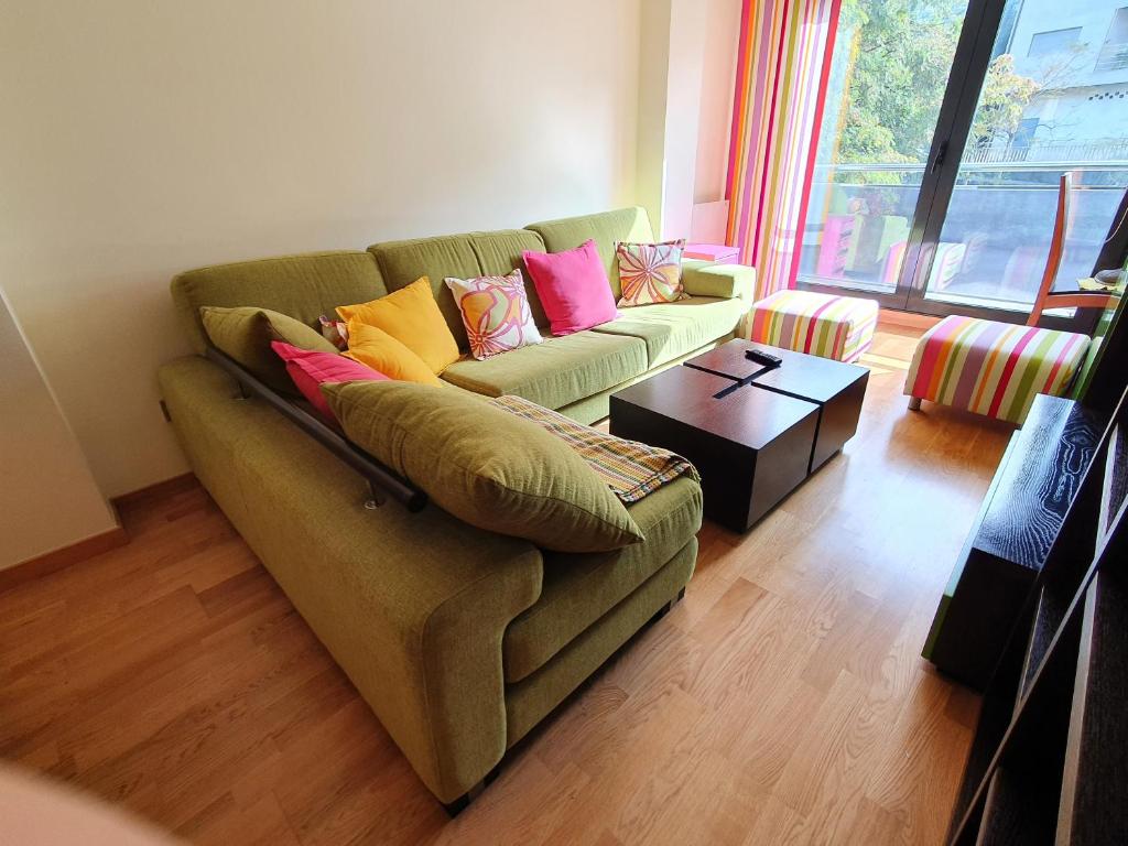 salon z zieloną kanapą i kolorowymi poduszkami w obiekcie PISO EN EL CENTRO DE NIGRAN CERCA DE PLAYA AMERICA w mieście Nigrán