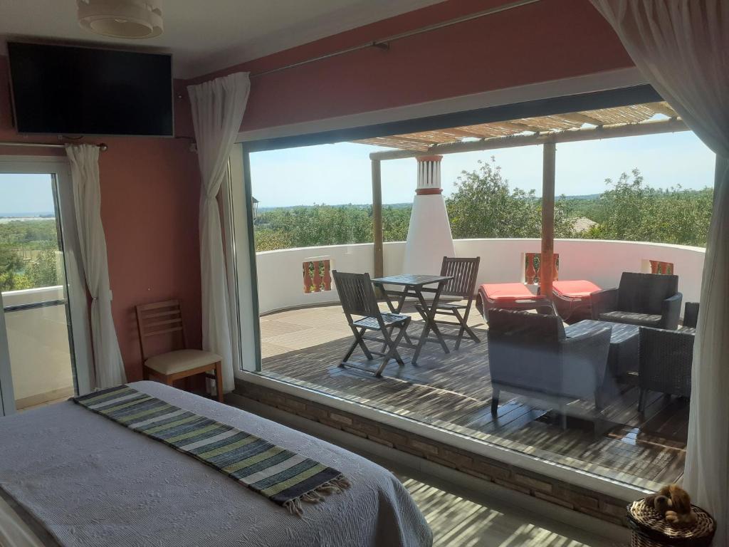 a bedroom with a bed and a balcony with a table and chairs at Alojamento local Patudos, Suite com terraço privado in Tavira