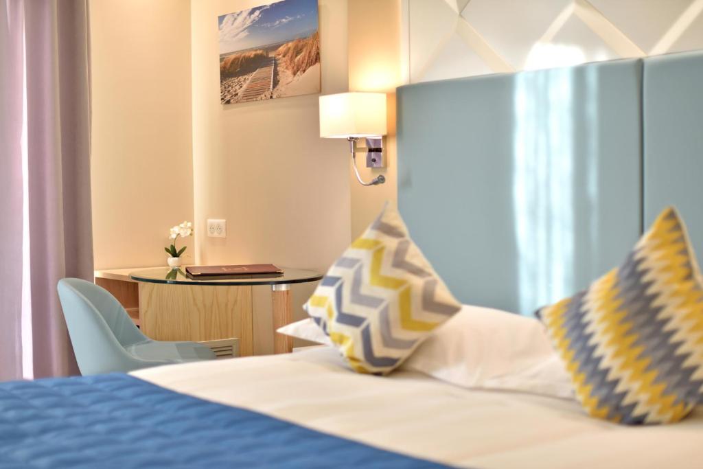 a hotel room with a bed with blue and yellow pillows at Hotel Tettola in Saint-Florent